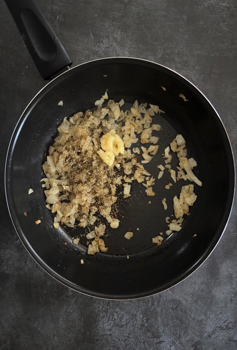 onions, garlic puree and herbs frying in a large pan.