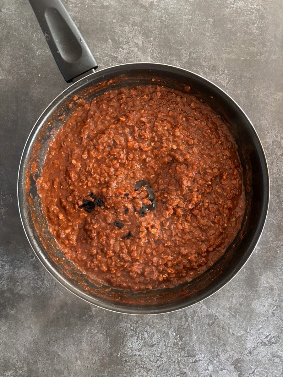 lentil bolognese cooking in frying pan. Balsamic vinegar poured in.